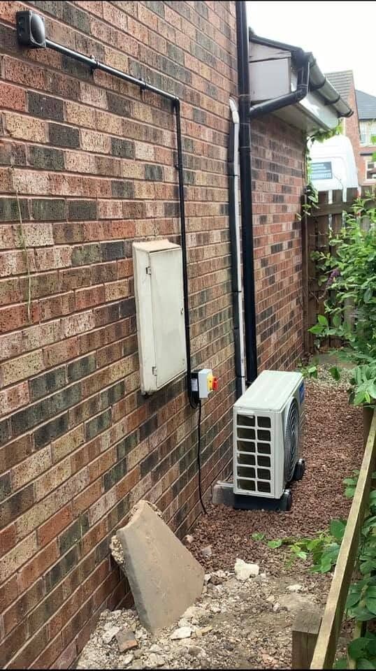 Air conditioning condenser mounted on brackets against a brick wall