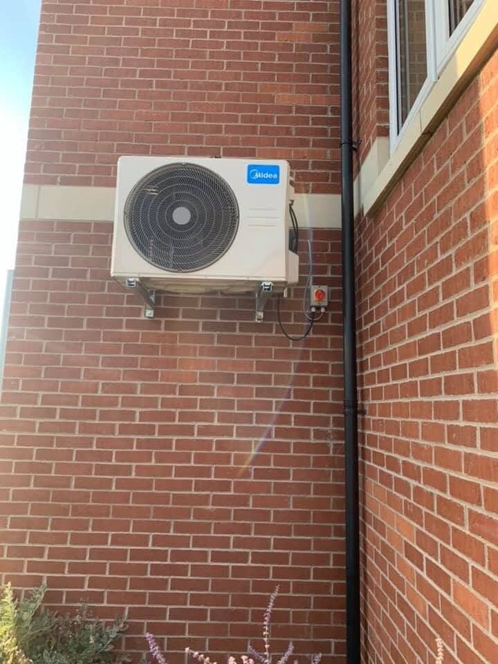 Air conditioning condenser fitted to a brick corner with routed pipework