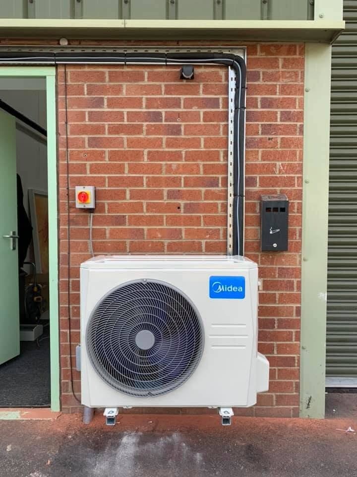 Air conditioning condenser installed beside a commercial doorway