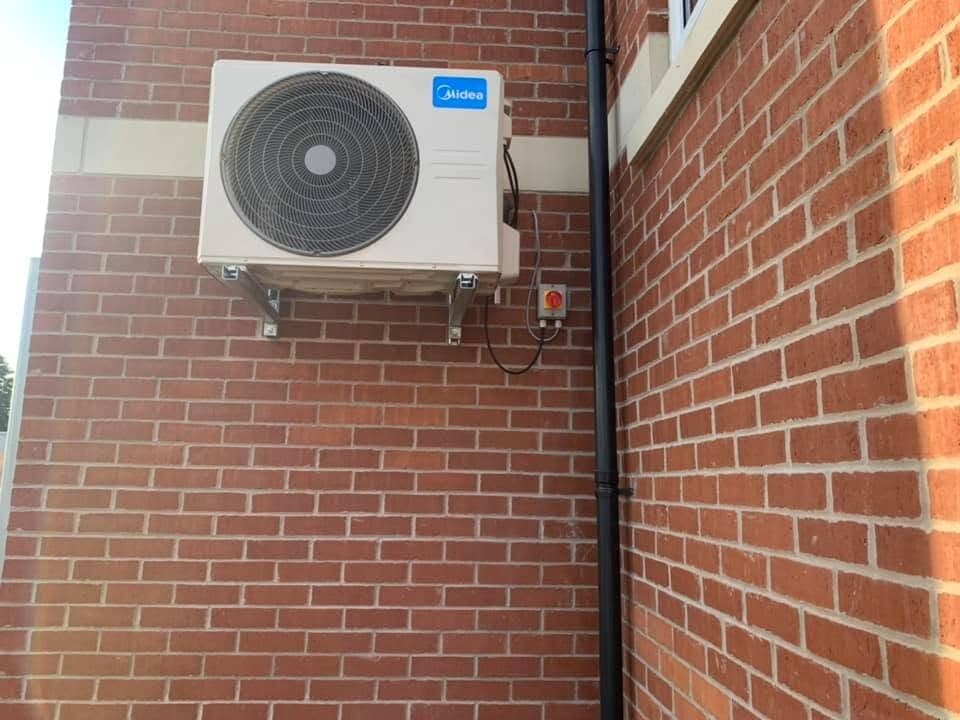 Air conditioning condenser bracket-mounted high on a brick elevation