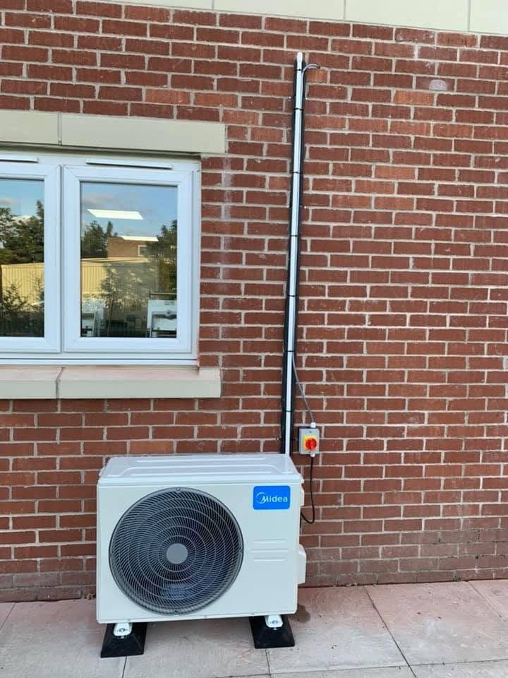 Air conditioning condenser installed beneath a window with tidy pipework