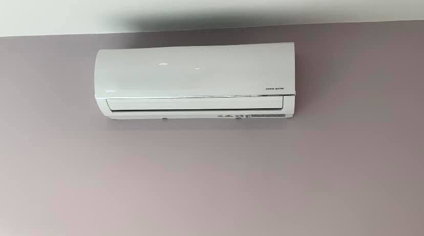 Wall-mounted air conditioning indoor unit fitted high on a plastered wall