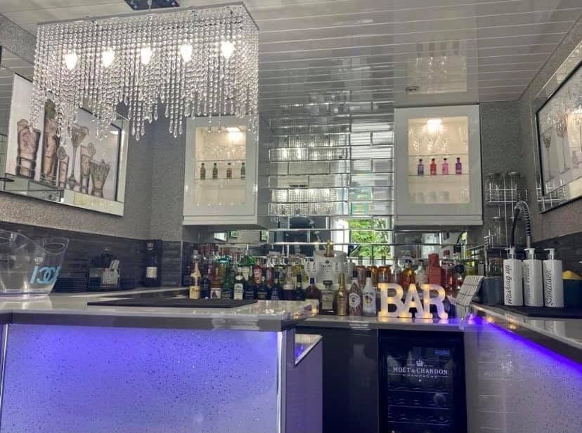 Bar fit-out with crystal chandeliers over the counter and colour-changing LED lighting