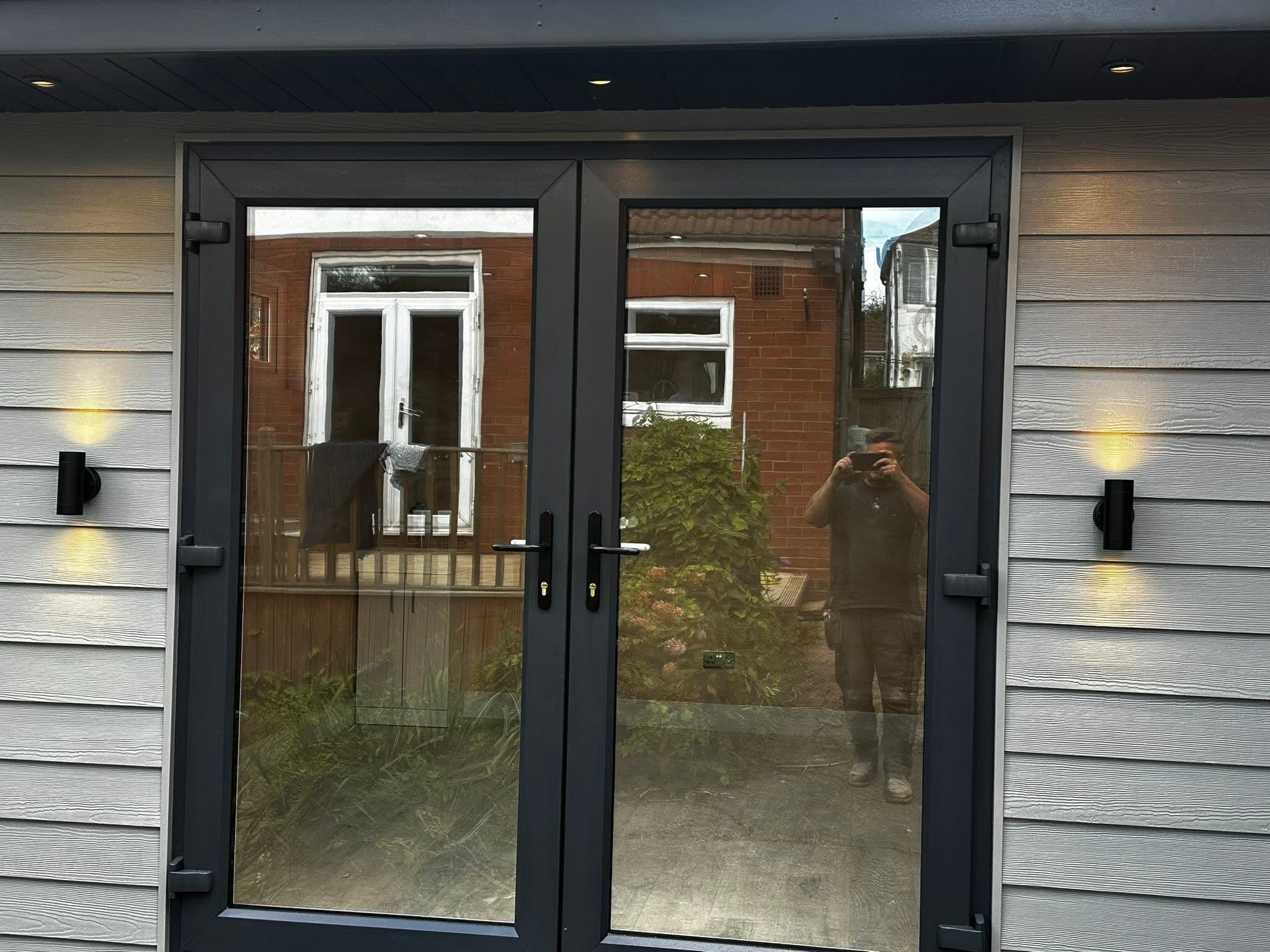 Bifold doors flanked by up-and-down wall lights at night