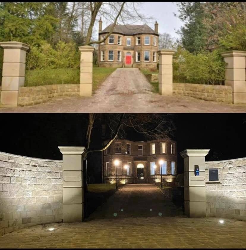 Lit stone gateposts and driveway approach to a country house at night
