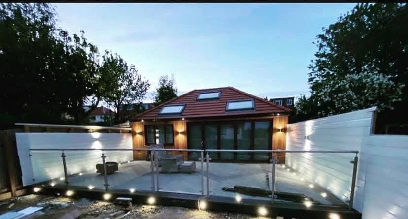 Extension and raised deck lit at dusk with recessed and wall lighting