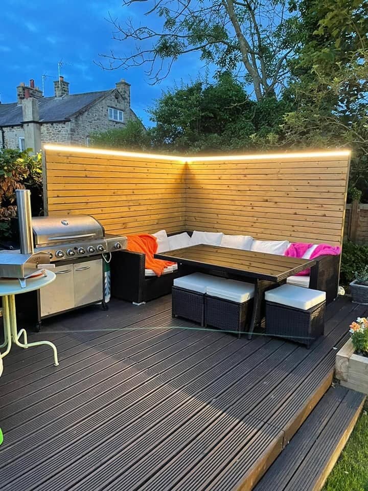 Garden seating and barbecue area lit by wall washers and deck lighting