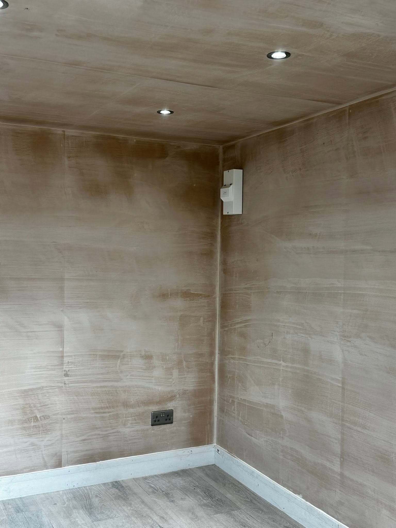 Corner of a finished garden room with ceiling downlights and skirting sockets