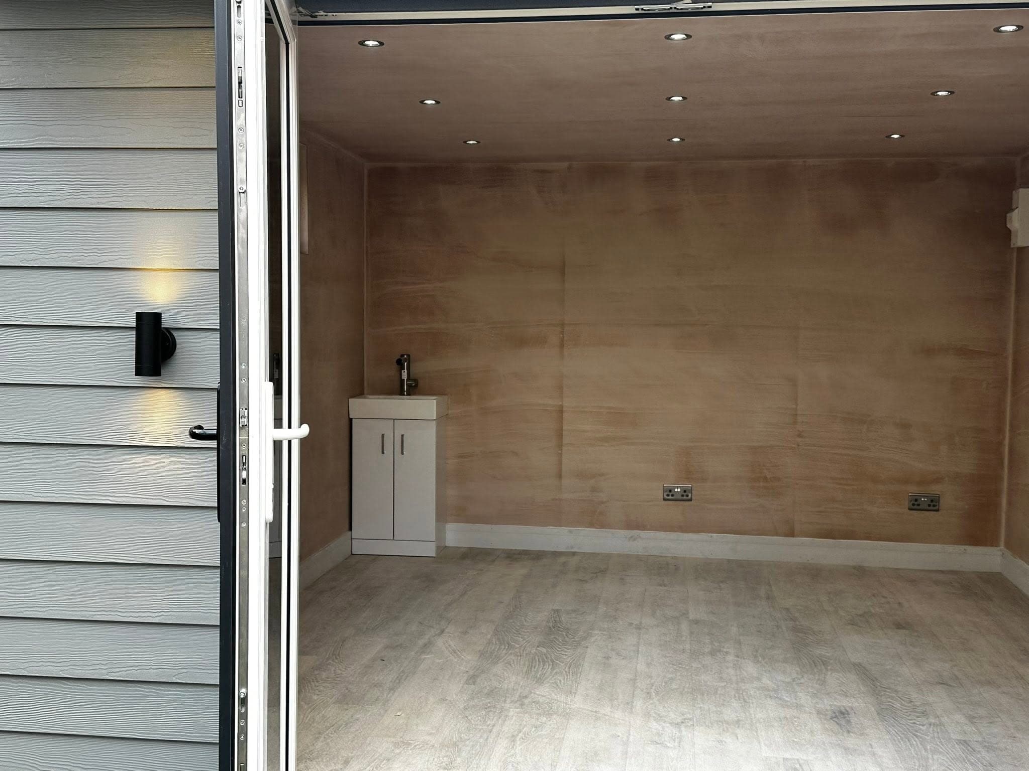 Wood-lined garden room interior lit by recessed downlights