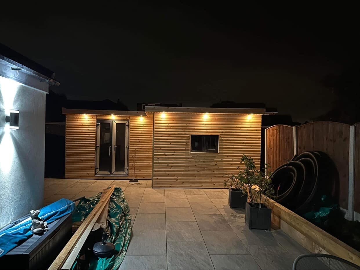 Garden room at night with lit decking and warm light spilling from the doors