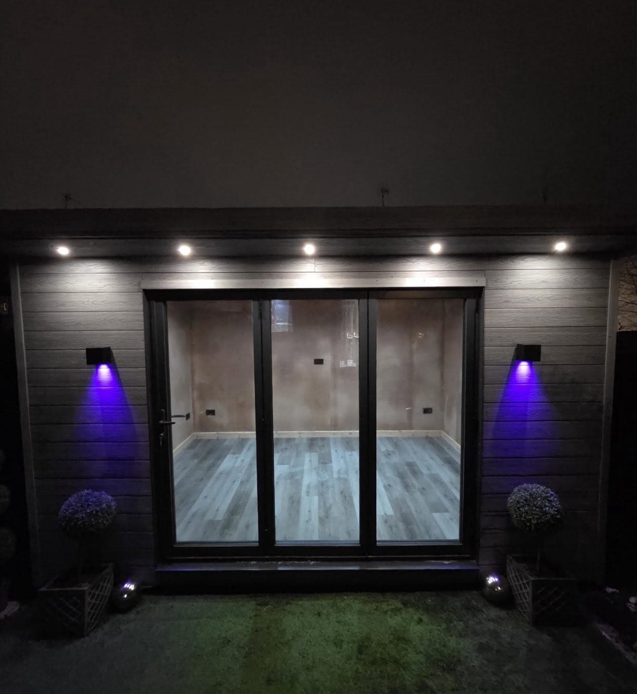 Garden room at night with colour-changing uplights washing the cladding