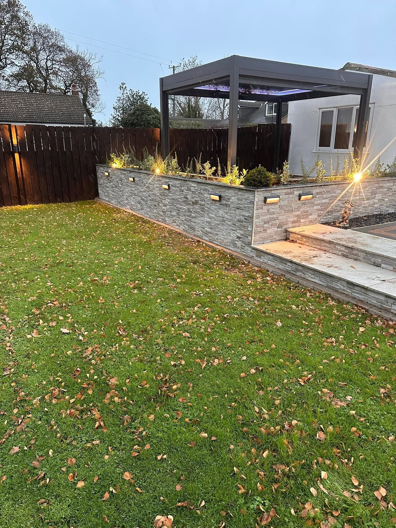 Lawn and retaining wall picked out by recessed brick lights after dark