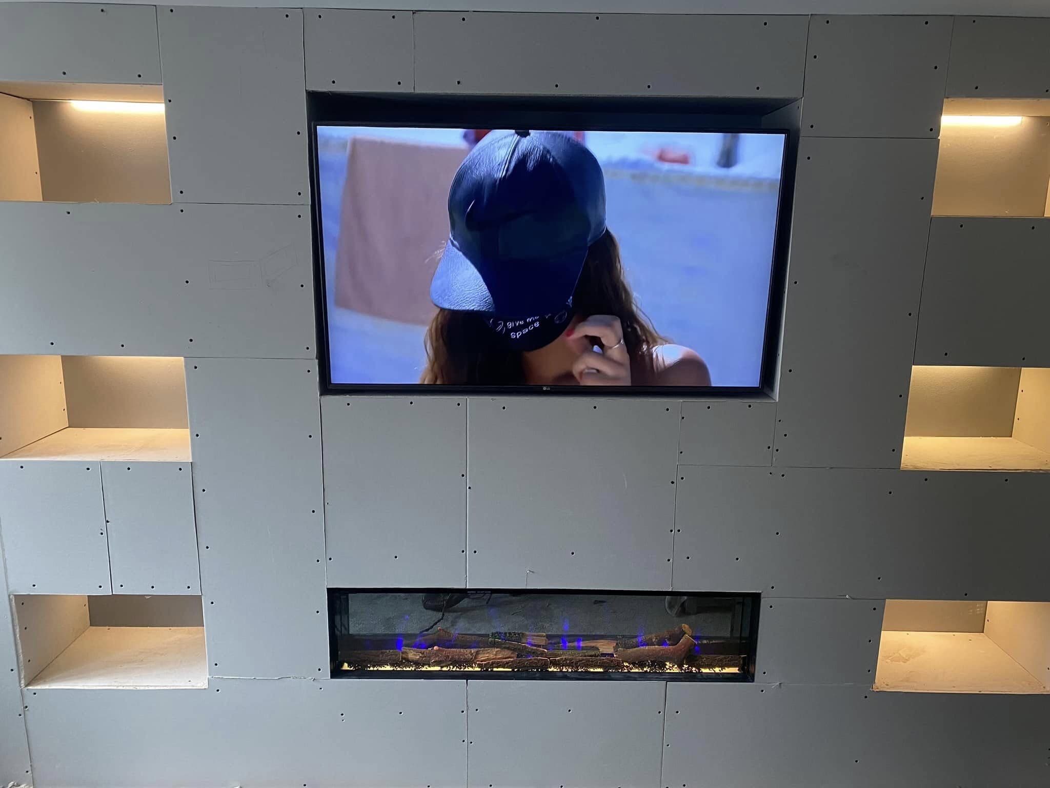 Finished media wall with wall-mounted television, inset electric fire and lit display niches
