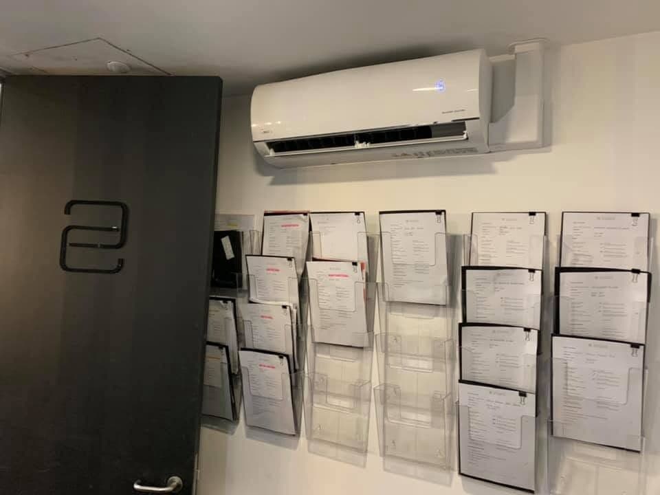Wall-mounted air conditioning unit in an office above wall-mounted racks