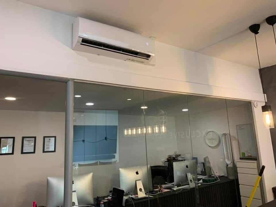 Office with a wall-mounted air conditioning unit above a glazed partition