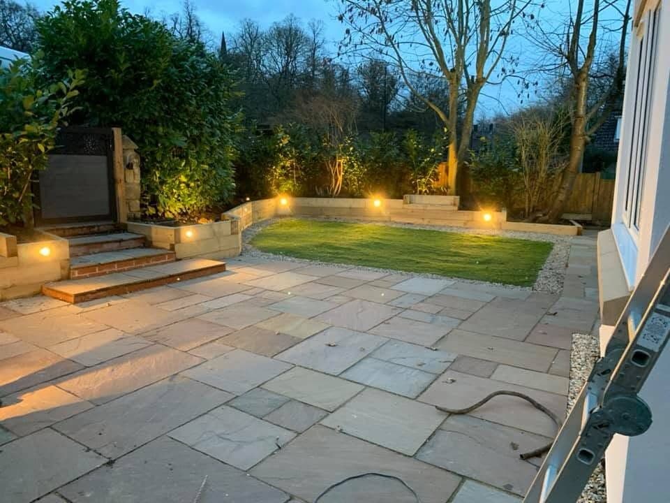 Flagged patio and steps lit by recessed wall lights with the garden beyond