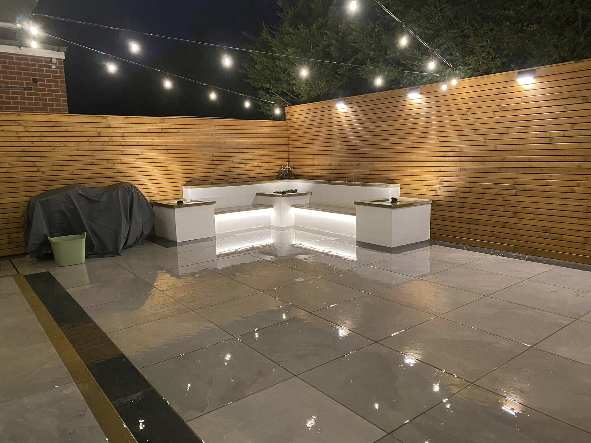 Lit patio and built-in outdoor kitchen with festoon lighting overhead