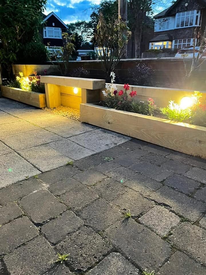 Patio and raised planters washed with warm light after dark