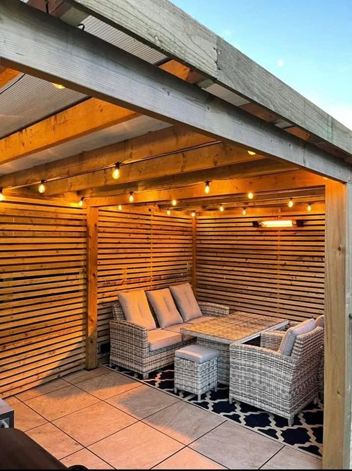 Slatted pergola with festoon lighting over a rattan seating area