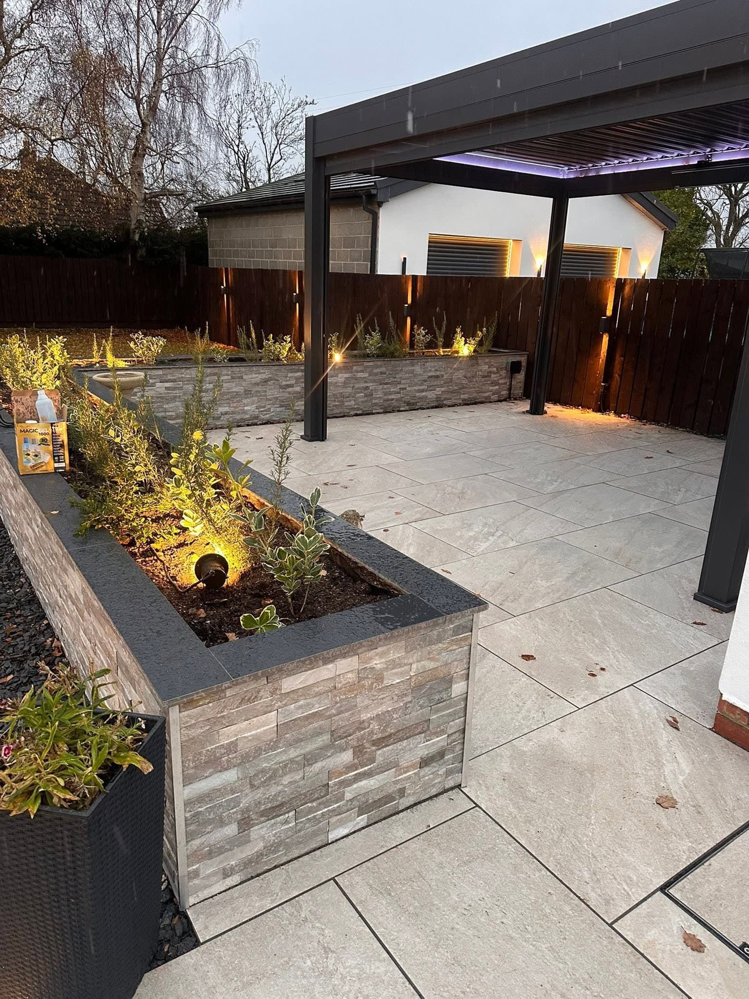 Long planter with in-bed spotlights alongside a lit patio and pergola