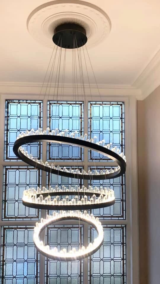 Tiered ring chandelier hung in a double-height stairwell window
