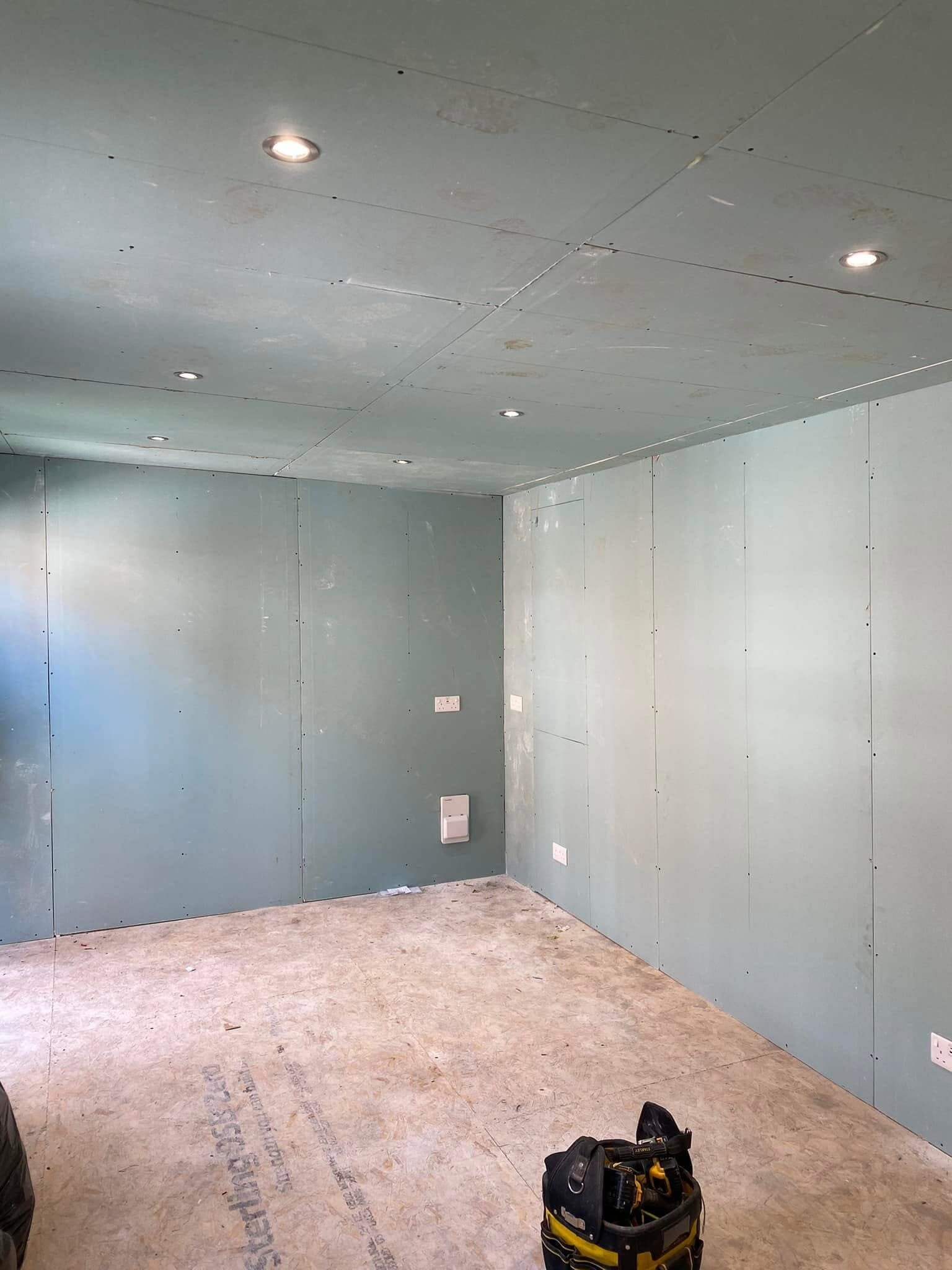 Freshly plastered room with recessed downlights installed to the ceiling